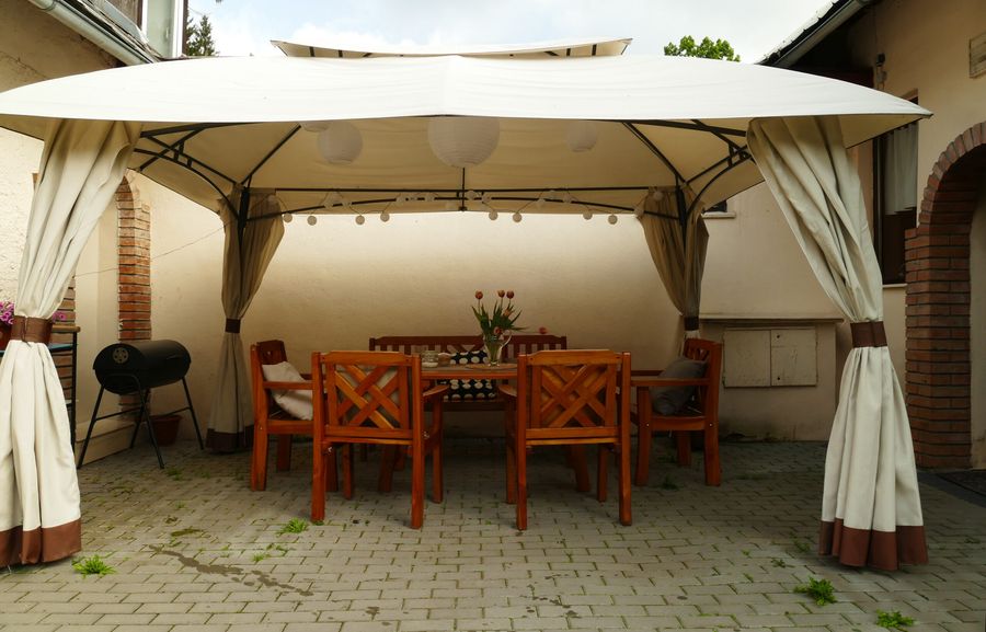 Venkovní terasa se stolem a židlemi pod markýzou